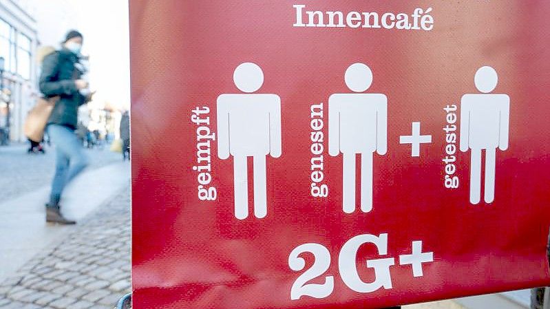 Ein Schild weist auf die 2G Plus Regel in einem Café im Ostseebad auf Rügen hin. Foto: Stefan Sauer/dpa