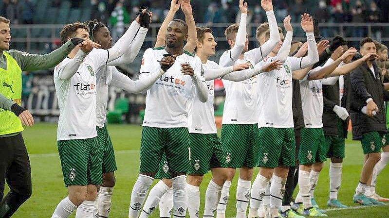 Nach dem Heimsieg gegen den FC Augsburg können die Gladbacher Spieler befreit mit den Fans feiern. Foto: Federico Gambarini/dpa