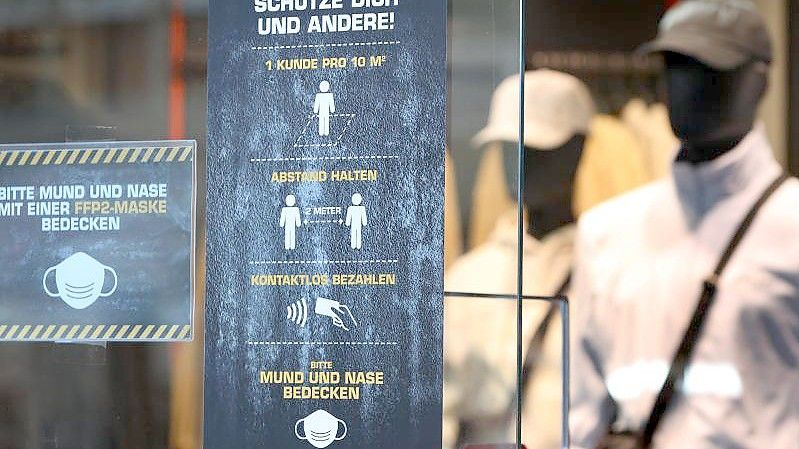 Ein Bekleidungsgeschäft in Augsburg weist auf verschiedene Corona-Regeln hin. Foto: Karl-Josef Hildenbrand/dpa