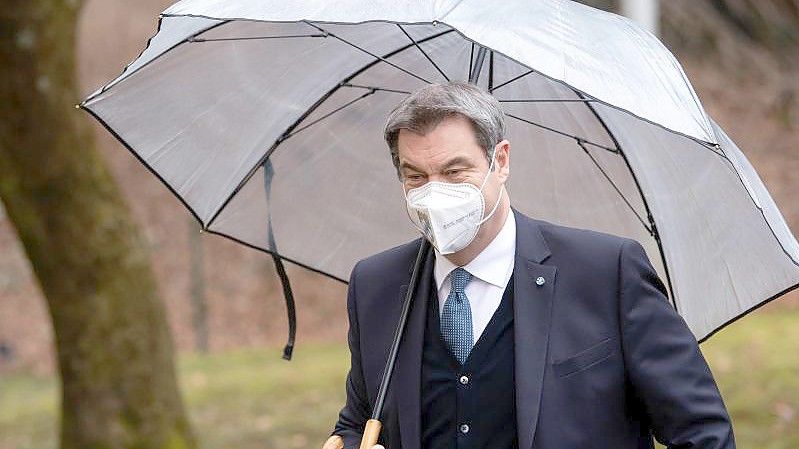 Markus Söder (CSU), Ministerpräsident von Bayern, kommt unter einem Regenschirm zur Pressekonferenz nach der Kabinettssitzung. Foto: Sven Hoppe/dpa