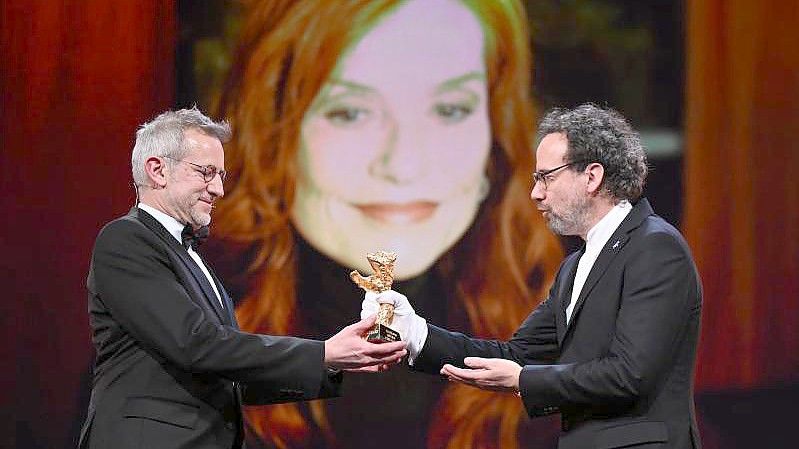 Regisseur Laurent Larivière nimmt stellvertretend für Isabelle Huppert den Goldenen Ehrenbären von Berlinaledirektor Carlo Chatrian (r) entgegen. Foto: Monika Skolimowska/dpa