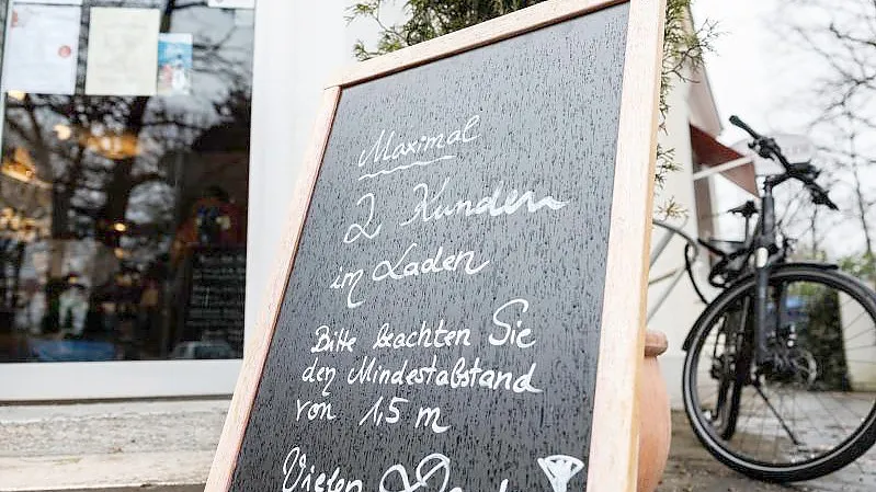 Eine Tafel vor einem Münchener Geschäft weist auf die Maximalanzahl von 2 Personen im Laden hin. Foto: Matthias Balk/dpa