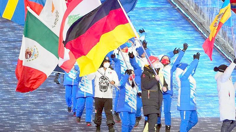 Zur Abschlussfeier der Olympischen Winterspiele 2022 trägt Bob-Anschieber Thorsten Margis für Deutschland die Fahne ins Stadion. Foto: Michael Kappeler/dpa