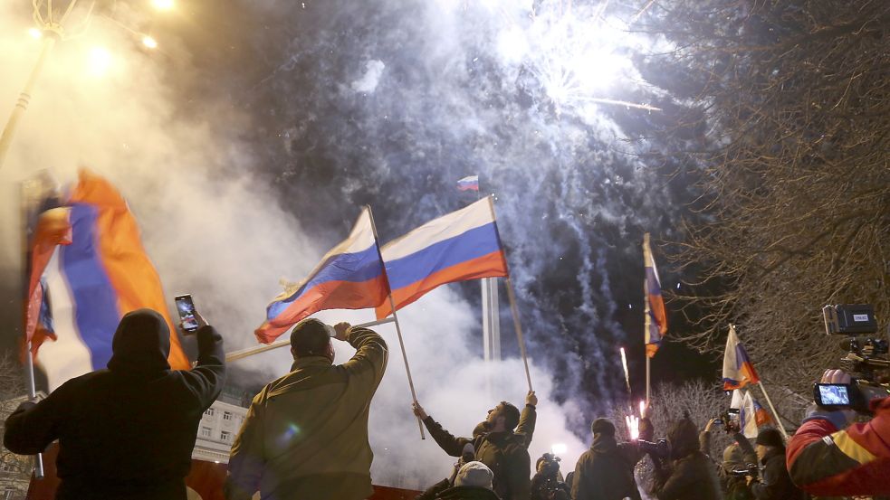 Ist das der Kriegsbeginn? Menschen schwenken russische Nationalflaggen und feiern die Anerkennung der Separatistengebiete in der Ostukraine durch Russland. Foto: picture alliance/dpa/AP