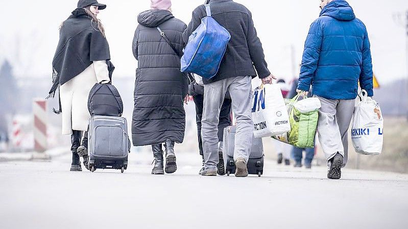 Geflüchtete Ukrainer gehen nach ihrem Grenzübertritt von Schehyni in der Ukraine nach Medyka in Polen. Foto: Michael Kappeler/dpa