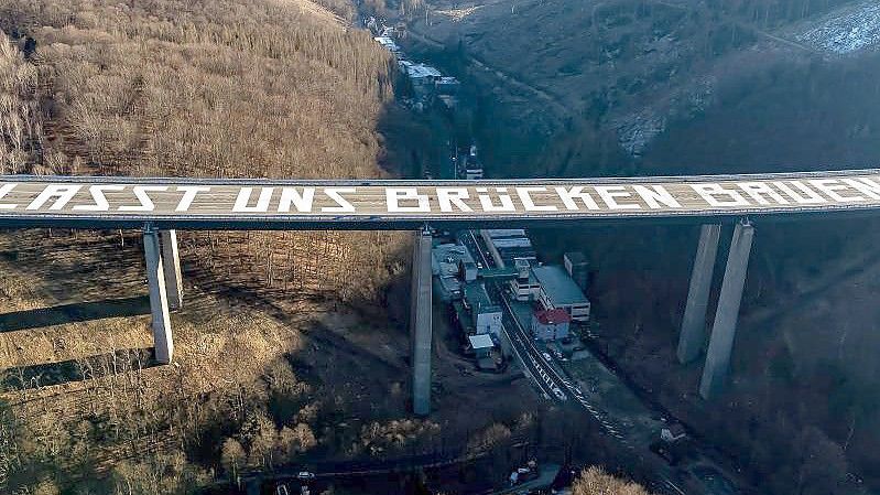 Die riesige Friedensbotschaft „Lasst uns Brücken bauen“ auf der gesperrten Rahmedetal-Brücke der Autobahn 45 bei Lüdenscheid. Foto: Markus Klümper/dpa