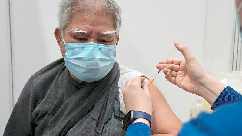 Hui Ngai-seng erhält in einem Impfzentrum in Hongkong seine erste Dosis des chinesischen Corona-Impfstoffs Sinovac. Foto: Kin Cheung/AP/dpa