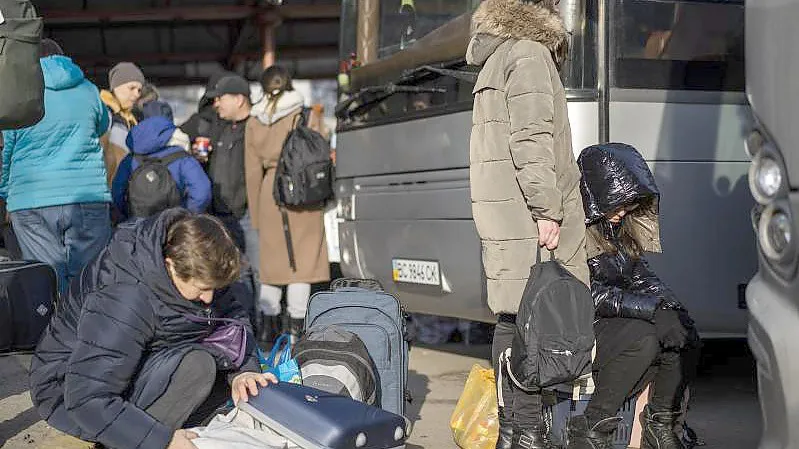 Ukrainische Bürger bereiten sich an einem Bahnhof im Westen der Ukraine vor, in einen Bus nach Polen einzusteigen. Foto: Bernat Armangue/AP/dpa