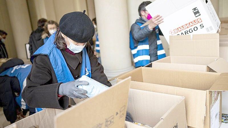 Freiwilige Helfer packen am Berliner Humboldt Forum Hilfsgüter in Kisten. Foto: Fabian Sommer/dpa