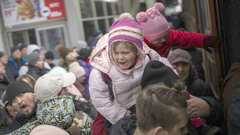 Menschen tragen ihre Kinder und versuchen am Bahnhof von Kiew, in einen Zug nach Lwiw zu steigen. Foto: Emilio Morenatti/AP/dpa