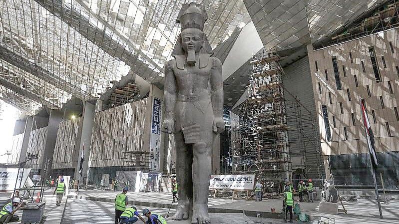 Arbeiter reinigen den Bereich neben der riesigen Statue des ägyptischen Pharaos Ramses II. in der Halle des Großen Ägyptischen Museums. Foto: Hassan Mohamed/dpa