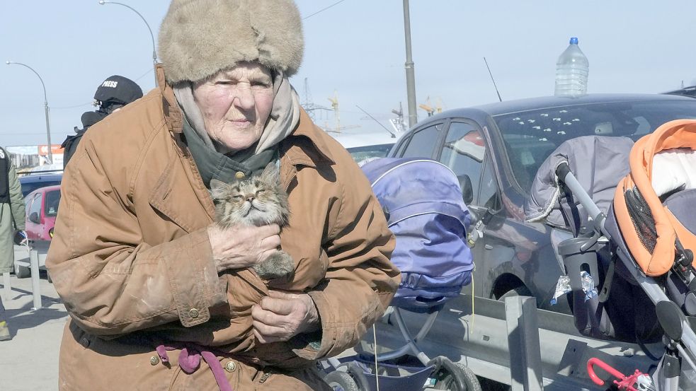 Eine ältere Frau trägt ihre Katze während der Flucht aus ihrer Heimatstadt auf der Straße in Richtung Kiew. Mehr als zwei Wochen nach dem Einmarsch in die Ukraine verstärken russische Truppen ihre Angriffe auf umkämpfte Städte. Foto: dpa/AP