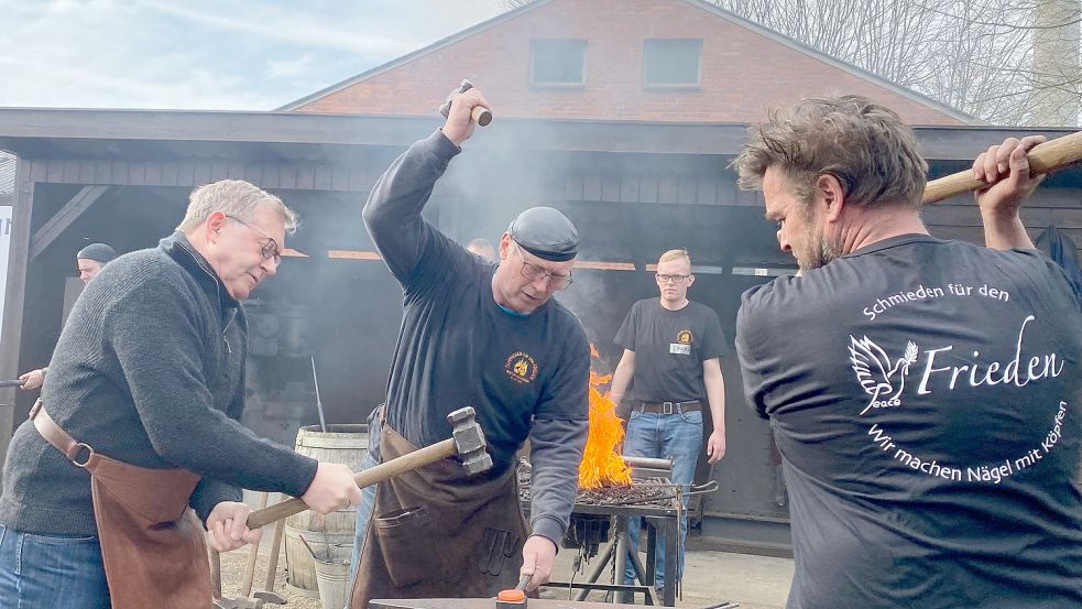 Stadtschmied und Initiator Alfred Bullermann (Mitte) mit 26 Schmiedekollegen. Unterstützung erhielt er vom Rotary-Club Friesoythe-Artland-Cloppenburg. Präsident Rüdiger Buder (links) griff auch selbst zum Hammer. Foto: Wimberg