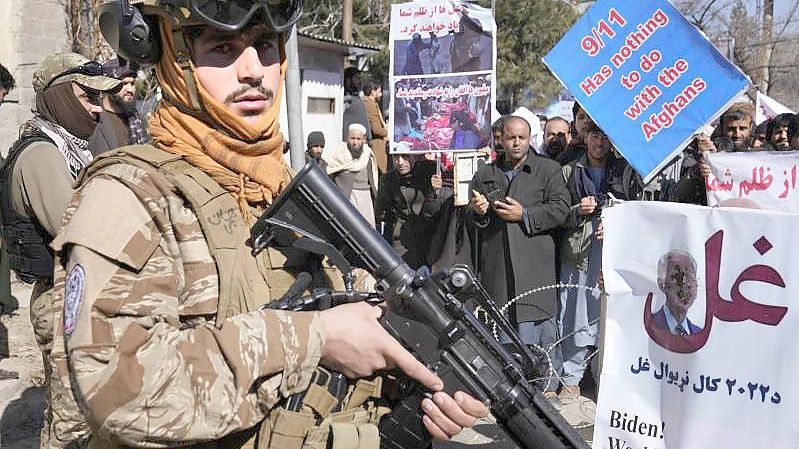 Ein bewaffneter Taliban Kämpfer steht während einer Demonstration neben afghanischen Demonstranten. Foto: Hussein Malla/AP/dpa