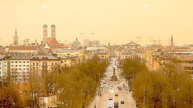 Eine Stadt in gelb und orange. Staub aus der afrikanischen Wüste färbt den Himmel in München. Foto: Sven Hoppe/dpa