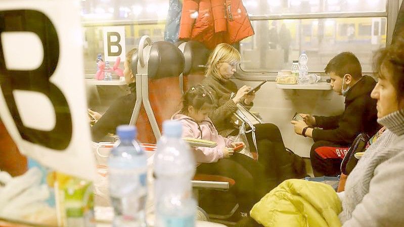 Flüchtlinge aus der Ukraine sitzen am Bahnhof in einem Personenzug in Richtung Deutschland. Foto: Zbigniew Meissner/PAP/dpa