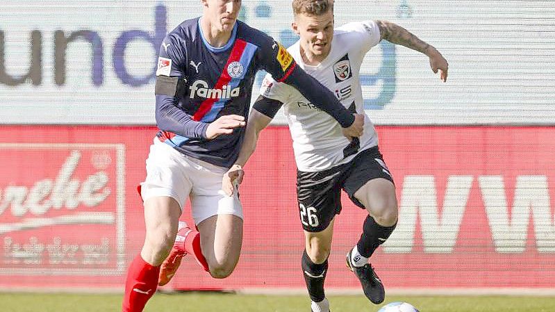 Phil Neumann (l) von Holstein Kiel und Ingolstadts Florian Pick versuchen an den Ball zu kommen. Foto: Frank Molter/dpa