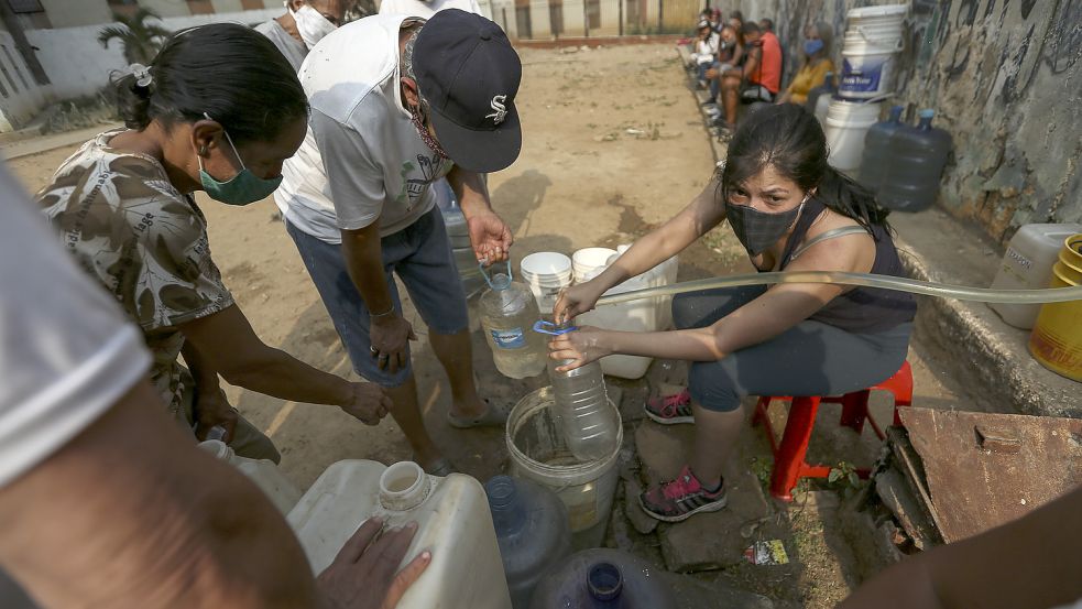 Menschen sammeln im Stadtteil Catia der venezianischen Hauptstadt Caracas Trinkwasser in Kanistern und Gefäßen. In vielen Haushalten im Land gibt es kein fließendes Wasser mehr. Die Wasserversorgung funktionieren teils nicht mehr. Die Coronavirus-Pandemie verschlimmert die Situation noch. (Archivbild) Foto: dpa/Pedro Rances Mattey