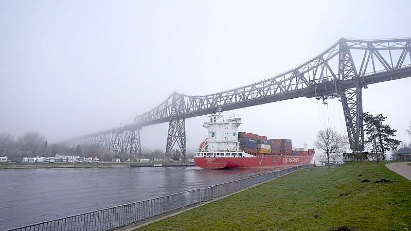 Ein Containerschiff im Frühnebel auf dem Nord-Ostsee-Kanal unter der Rendsburger Hochbrücke Anfang März 2022. Foto: Marcus Brandt/dpa