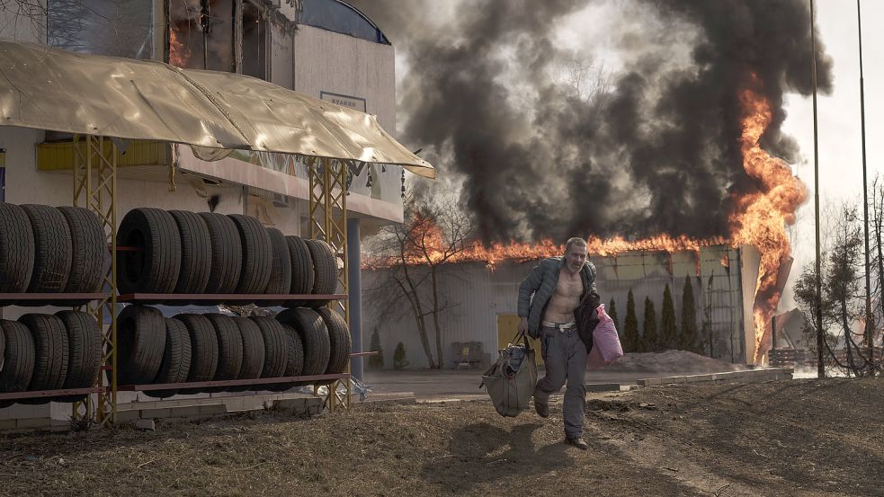 Seit dem 24. Februar tobt der Krieg in der Ukraine: Ein Mann rettet am Freitag Gegenstände aus einem brennenden Geschäft nach einem russischen Angriff in Charkiw. Foto: Dana/AP/DPA