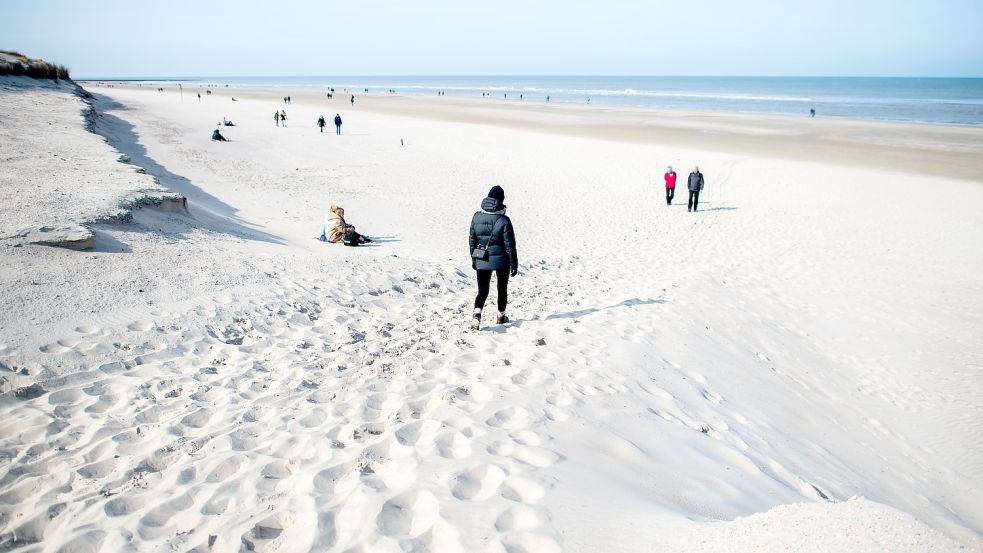 Spaziergänger gehen am Strandabschnitt „Weiße Düne“ auf Norderney nahe der Abbruchkante entlang. Nach den schweren Winterstürmen mit Sturmfluten und erheblichen Sandverlusten will das Land Niedersachsen den betroffenen Ostfriesischen Inseln finanziell helfen. Foto: Dittrich/DPA