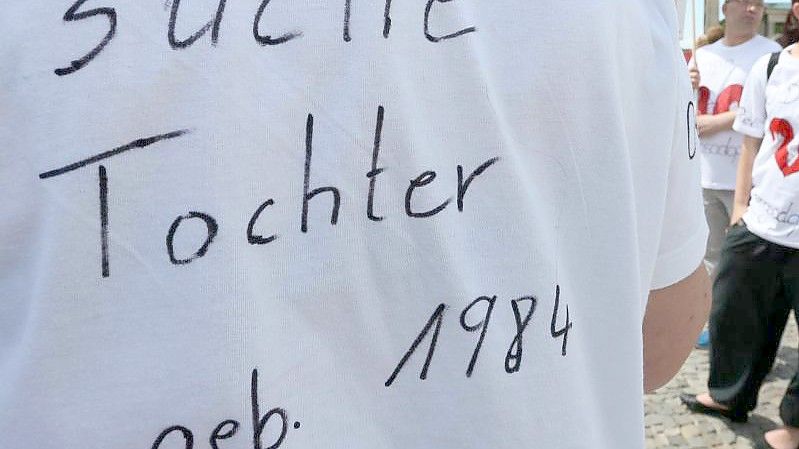"Suche Tochter, geb. 1984" steht auf dem T-Shirt einer Frau bei einer Kundgebung. Foto: Stephanie Pilick/dpa