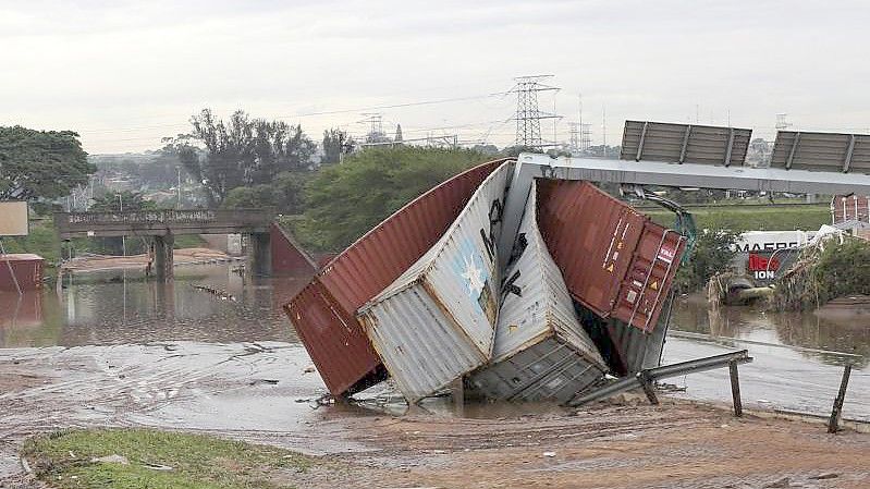 Beschädigte Schiffscontainer sind durch ungewöhnlich heftige Niederschläge weggetragen und zerstört worden. Foto: Str/AP/dpa