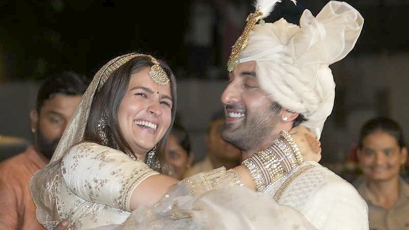Die Bollywood-Schauspieler Ranbir Kapoor (r) und Alia Bhatt nach ihrer Hochzeit vor ihrem Haus in Mumbai. Foto: Rajanish Kakade/AP/dpa