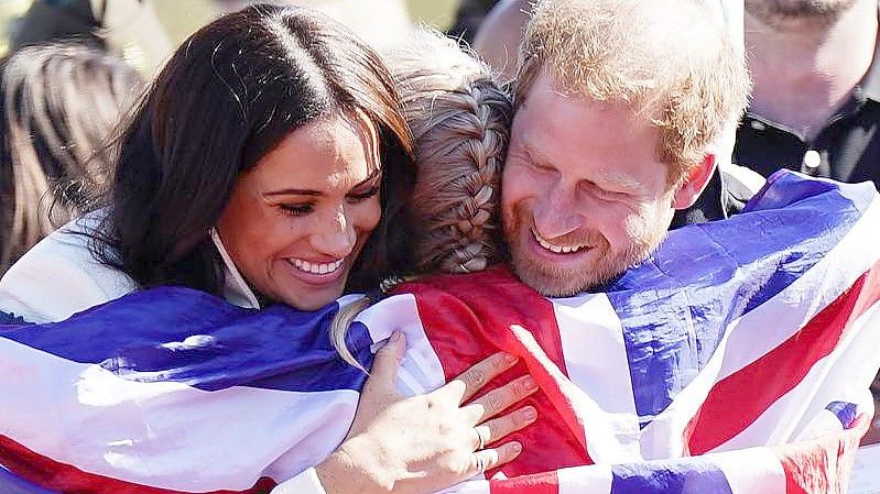 Prinz Harry (r) und Meghan (l) umarmen die britische Teilnehmerin Lisa Johnston. Foto: Aaron Chown/PA Wire/dpa