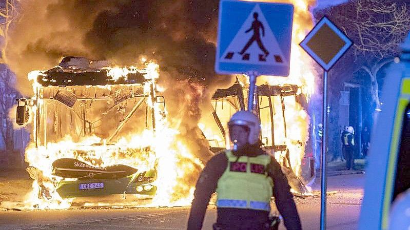 Bereitschaftspolizisten im schwedichen Malmö beobachten einen brennenden Stadtbus. Foto: Johan Nilsson/TT NEWS AGENCY/AP/dpa