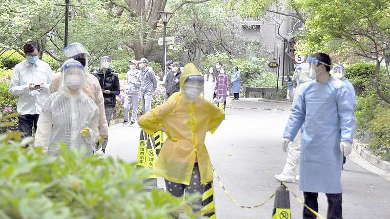 Bewohner einer Wohnanlage in Shanghai warten auf die Durchführung von PCR-Tests. Foto: kyodo/dpa