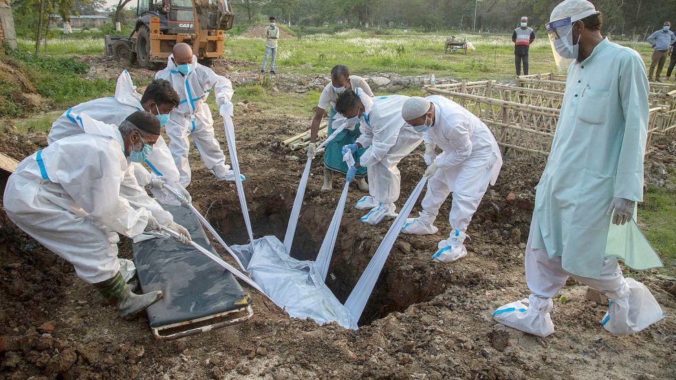 Angehörige und städtische Mitarbeiter in Schutzanzügen begraben in Gauhati einen Menschen, der an Covid-19 gestorben ist. Foto: Anupam Nath/AP/dpa