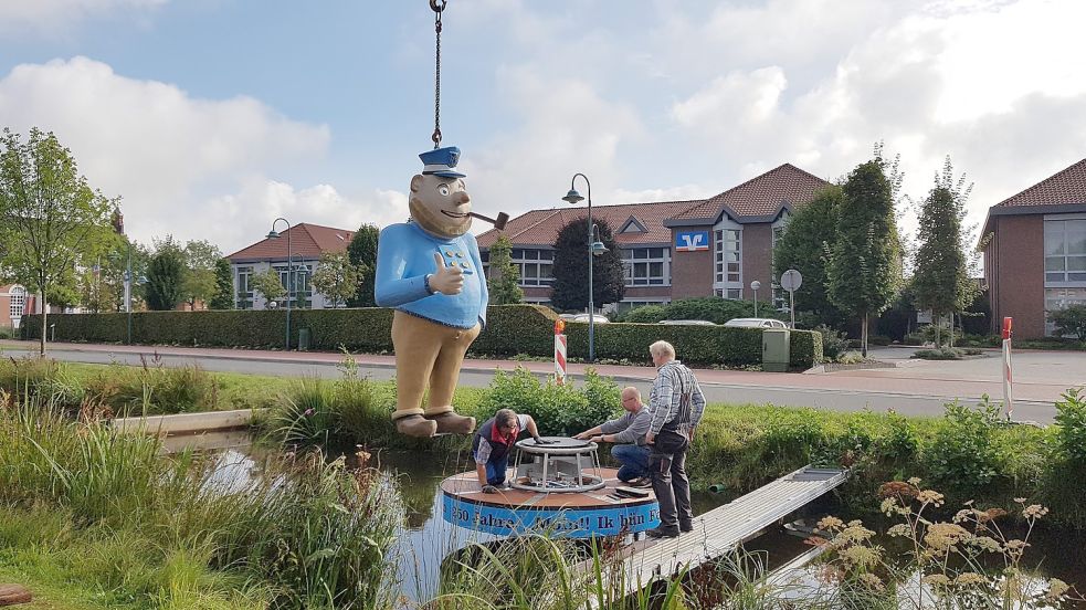 •Achim Kuhnert (von links), Andreas Kracke und Uwe Braak bauten die Fokko-Figur im Kanal am Rathaus in Rhauderfehn auf.