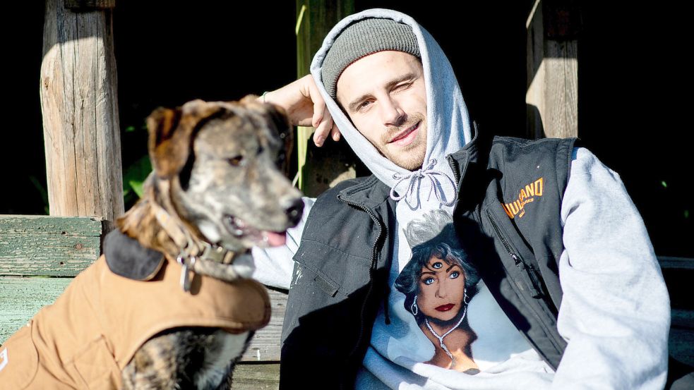 Der Influencer Fynn Kliemann sitzt mit seinem Hund auf dem Hof „Kliemannsland“ im Kreis Rotenburg (Wümme). Die Kreativstätte des Unternehmers wird von der EWE mit grünem Strom aus Ostfriesland versorgt. Foto: Dittrich/DPA