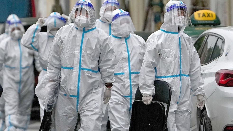 Arbeiter laufen zu einem Wohnkomplex in Peking, der wegen steigener Coronazahlen komplett abgeriegelt wurde. Foto: Andy Wong/AP/dpa