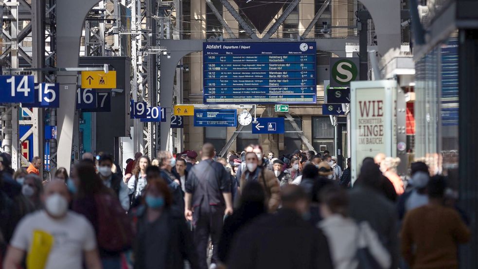 Reisende gehen durch die Bahnhofshalle in Frankfurt/Main. Die Debatte um die Maskenpflicht in öffentlichen Transportmitteln geht weiter. Foto: Hannes Albert/dpa