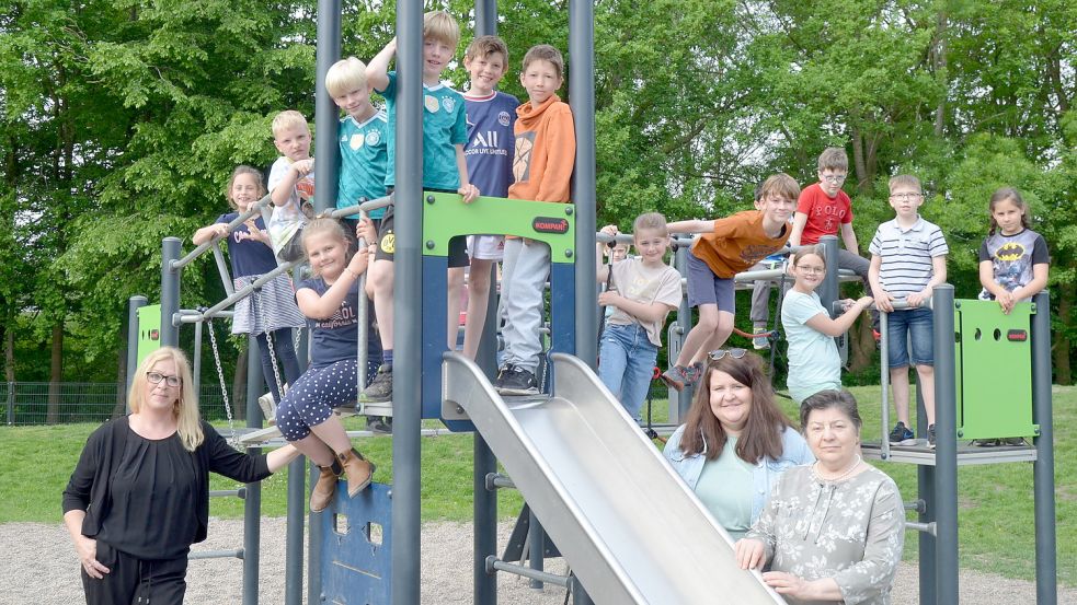 Seit Kurzem ist das erste Flüchtlingskind aus der Ukraine an der Grundschule in Ramsloh angekommen: Der zehnjährige Nazar Shiker (auf dem Turm, mit orangefarbenem Oberteil) mit der Klasse 3b, deren Klassenlehrerin Kristiane Fisse (stehend, 2. von rechts), seiner Sprachlehrerin Anna Sartorius (stehend, rechts) und Schulleiterin Britta Tegelkamp (stehend, links) beim Klettergerüst auf dem Schulhof. Foto: Fertig