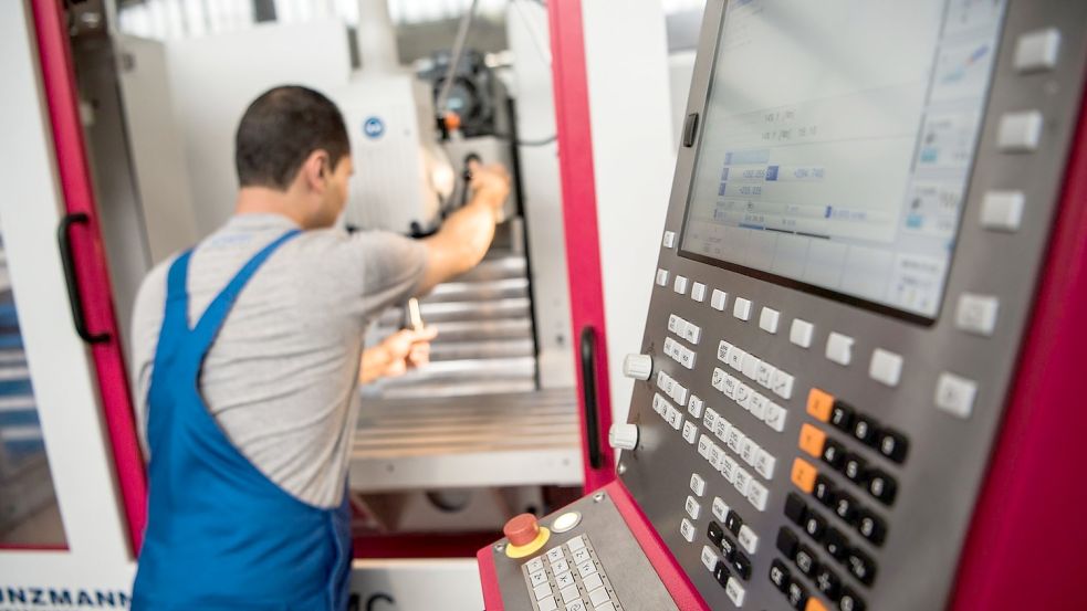 Ein Auszubildender, der 2012 aus dem Iran nach Deutschland floh, setzt in einem Mainzer Betrieb ein Werkzeug in eine Fräsmaschine ein. Die großen deutschen Aktiengesellschaften beschäftigen insgesamt nur wenige Flüchtlinge. Foto: Andreas Arnold/dpa