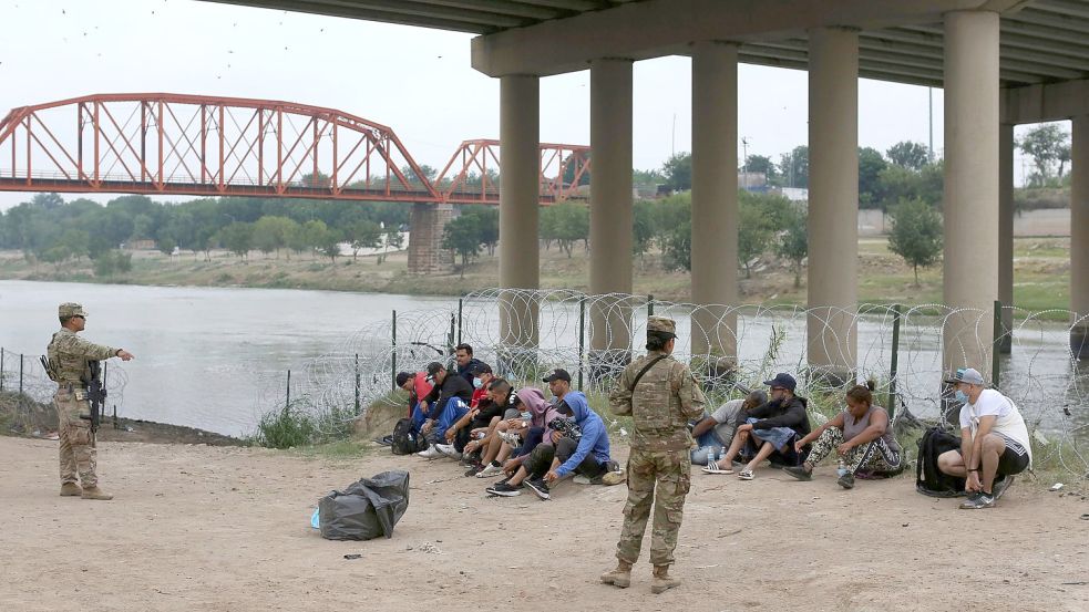 Migranten warten am Rio Grande auf die Ankunft von US-Grenzschutzbeamten. Eine Regelung der Gesundheitsbehörde CDC ermöglicht unter Verweis auf pandemiebedingte Gesundheitsrisiken, die meisten ohne gültige Papiere ins Land gelangten Menschen rasch wieder abzuschieben. Foto: Dario Lopez-Mills/AP/dpa