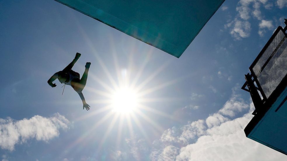 Ein Mann springt im Freibad vom Zehn-Meter-Turm. Foto: Oliver Berg/dpa
