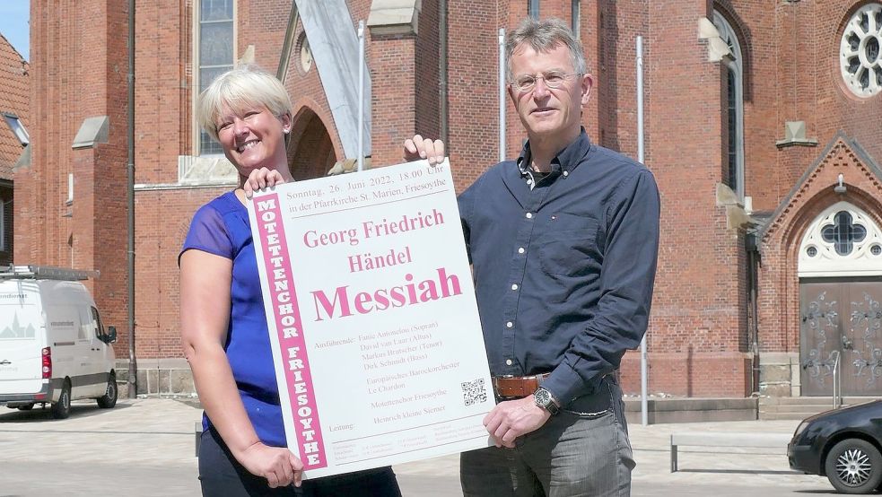 Claudia Oltmanns, zweite Vorsitzende des Friesoyther Motettenchors, und dessen Chorleiter Heinrich kleine Siemer bei der Präsentation des Plakats vor der Pfarrkirche St. Marien in Friesoythe. Foto: privat