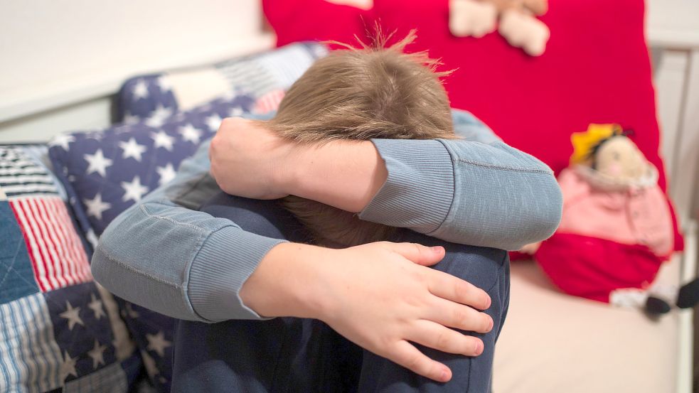 Ein Junge kauert sich auf seinem Bett zusammen. Aufsichtspersonen in Vereinen oder Kirchen können bisher nur strafrechtlich belangt werden, wenn sie sexuellen Missbrauch von Kindern absichtlich ermöglichen. Symbolfoto: Armer/DPA