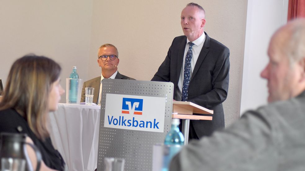 Vorstands-Vorsitzender Uwe Brechtezende (hinten, stehend) präsentierte auf der Vertreterversammlung die Bilanz der Volksbank Westrhauderfehn für das Jahr 2021. Neben ihm sitzt Aufsichtsratsvorsitzender Wolfgang Mengers. Fotos: Zein