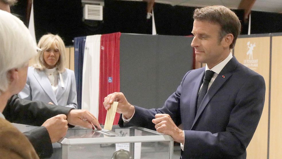 Vor schwierigen Zeiten: Emmanuel Macron, Präsident von Frankreich, wirft seinen Stimmzettel in eine Wahlurne, während seine Frau Brigitte Macron daneben steht. Foto: Spingler/AP Pool/dpa