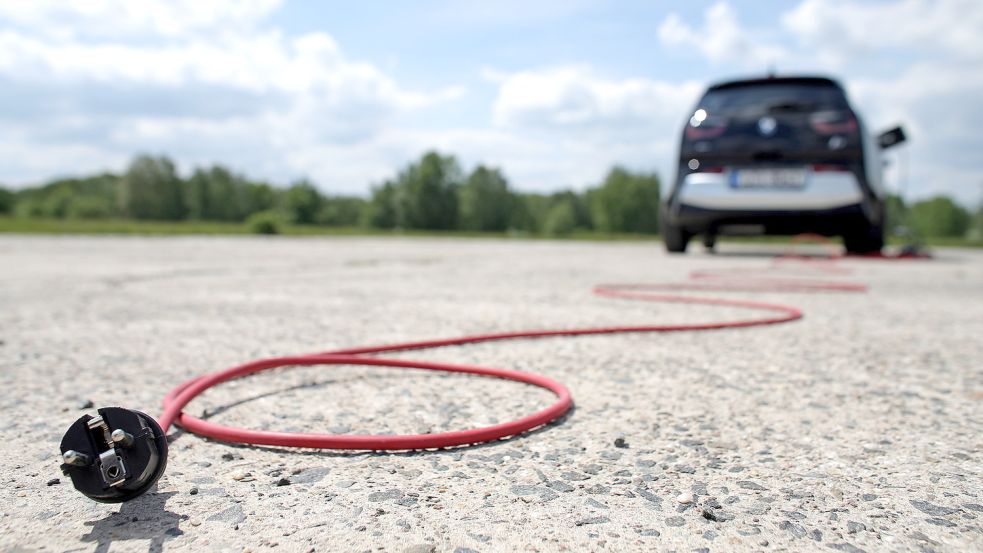 Bald Schluss mit der Förderung? Ein rotes Stromkabel liegt hinter einem elektrisch angetriebenen BMW i3. Foto: Woitas/dpa