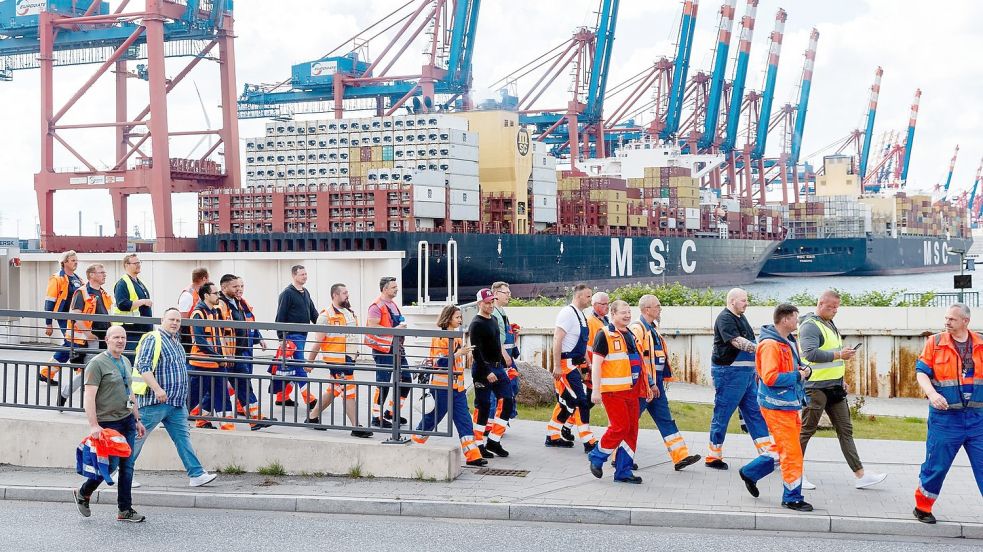 Hafenarbeiter in Hamburg gehen zu einer Streikversammlung. Foto: Markus Scholz/dpa