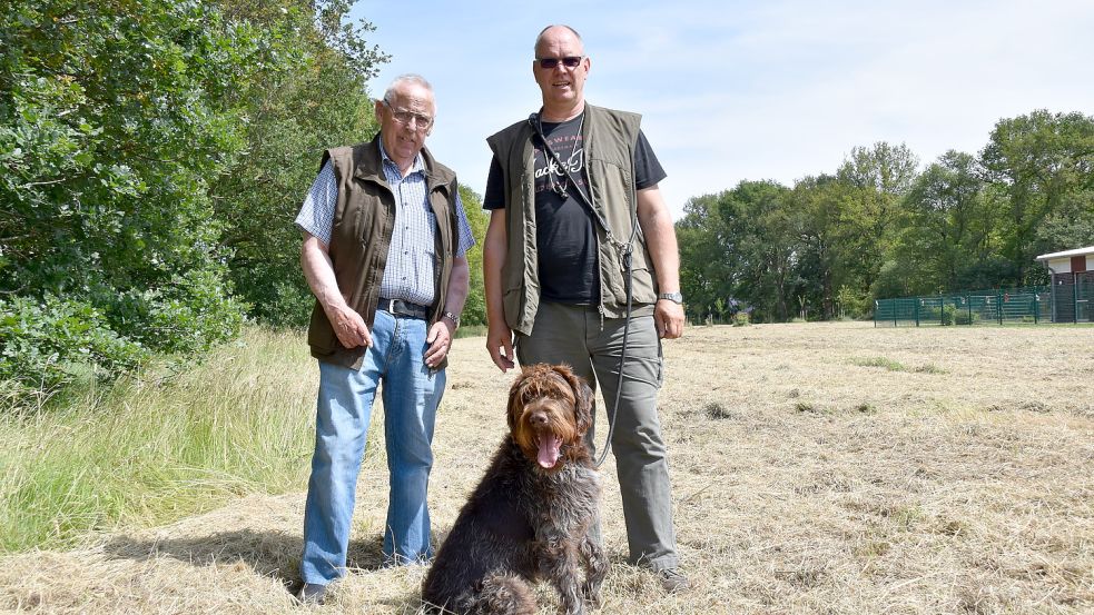 Toni Boyken (links) und Enno Coners mit Jagdhund Malik auf der gemähten Streuobstwiese in Steenfelde. Foto: Wehry