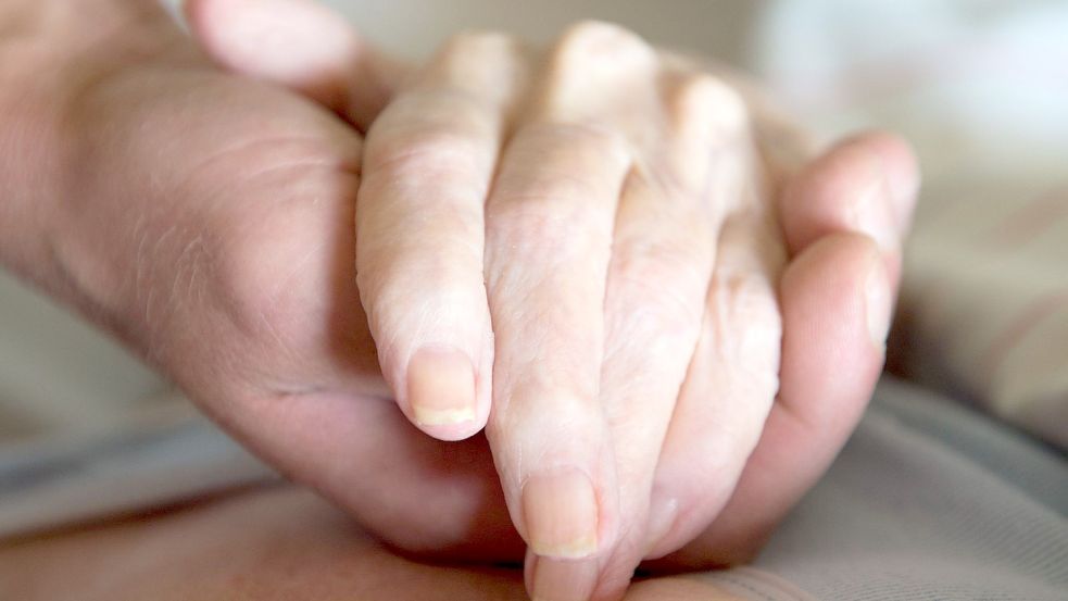 Ein Altenpfleger hält in einem Pflegeheim die Hand einer Frau. Der Bundestag hat sich mit konkreten Vorschlägen zur Regelung der Sterbehilfe in Deutschland befasst. Foto: Sebastian Kahnert/zb/dpa