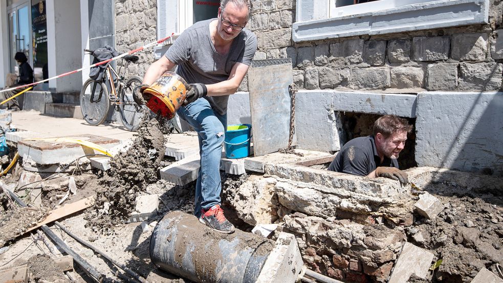 Stolberg wenige Tage nach der Flut: Zwei freiwillige Helfer räumen den Schlamm aus dem Keller einer Gaststätte. Foto: Marius Becker/dpa