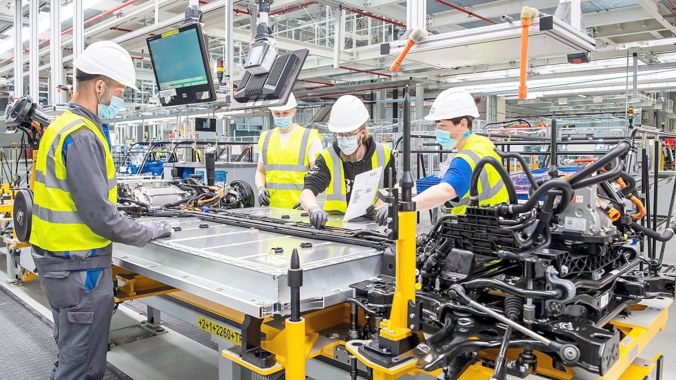 Mitarbeiter von VW in Emden arbeiten am Unterboden mit der Batterie für den ID.4. Im Herbst stehen die Verhandlungen für den Haustarif des Autobauers an. Foto: Schuldt/DPA